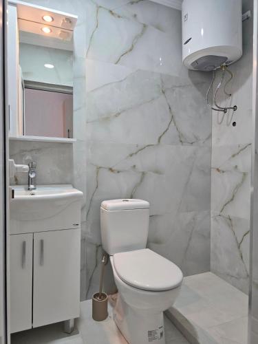 a white bathroom with a toilet and a sink at Apartments Duga Ulcinj in Ulcinj