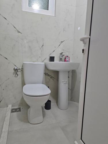 a white bathroom with a toilet and a sink at Apartments Duga Ulcinj in Ulcinj