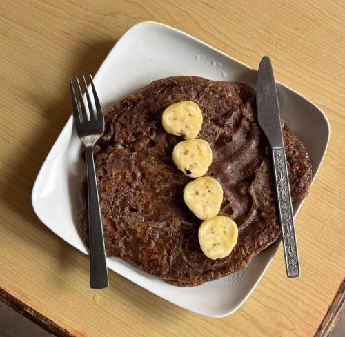 a plate of chocolate pancakes with bananas on top at Fewa Homestay and Retreat in Pokhara