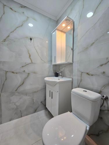 a white bathroom with a toilet and a sink at Apartments Duga Ulcinj in Ulcinj