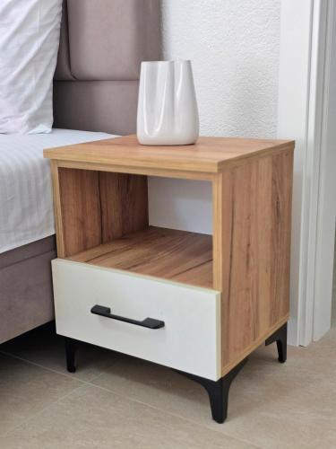 a wooden bedside table with a drawer and a vase on it at Apartments Duga Ulcinj in Ulcinj