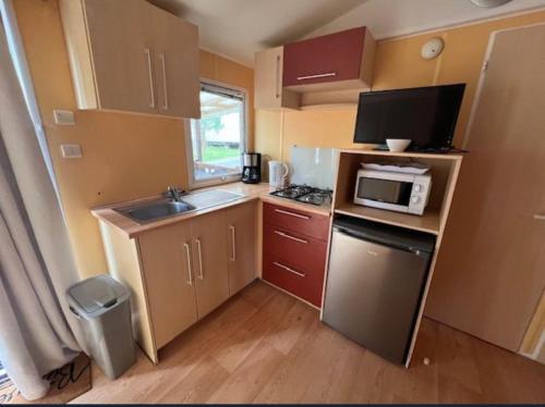 une petite cuisine avec un évier et un micro-ondes dans l'établissement MOBIL HOME proche de la mer, à Grand-Village-Plage
