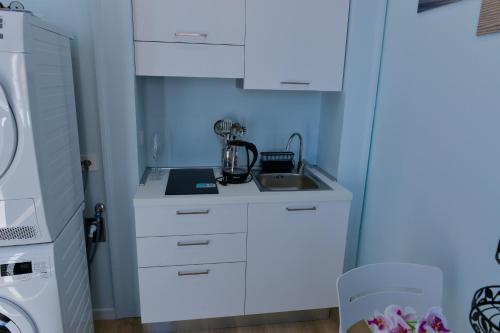 a kitchen with white cabinets and a sink at L'Aurora Azzurra -Luxury Suites Sorrento coast in Piano di Sorrento