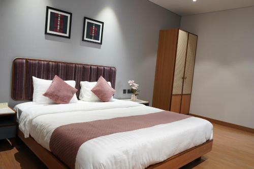 a bedroom with a large bed with pink pillows at Hotel The Sankalp Retreat in Bhavnagar