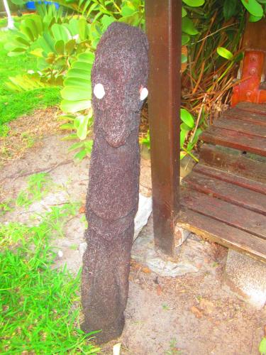 a stone statue of a bird standing next to a bench at Poétitude in Bourail