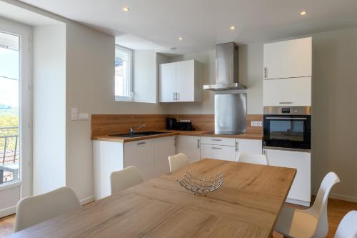 une cuisine avec une table en bois et des armoires blanches dans l'établissement Gîte dans un village Aveyronnais, à Lunac