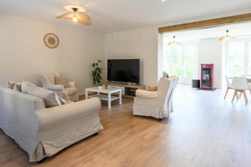 Il comprend un salon doté d'un mobilier blanc et d'une télévision à écran plat. dans l'établissement Gîte dans un village Aveyronnais, à Lunac