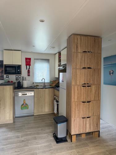 a kitchen with a large wooden cabinet in the middle at Mobil-home plage des casernes in Seignosse