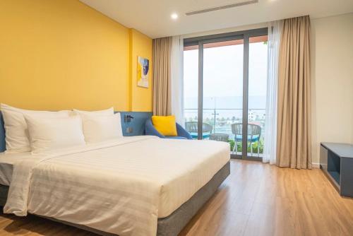 a hotel room with a bed and a large window at FLAMINGO Ibiza HaiTien - Ivy Abtel in Thanh Hóa