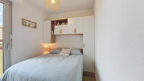 une chambre avec un lit dans une pièce blanche dans l'établissement V-Landes 10-Joli petit appartement proche lac marin dans résidence avec piscine, à Vieux-Boucau-les-Bains