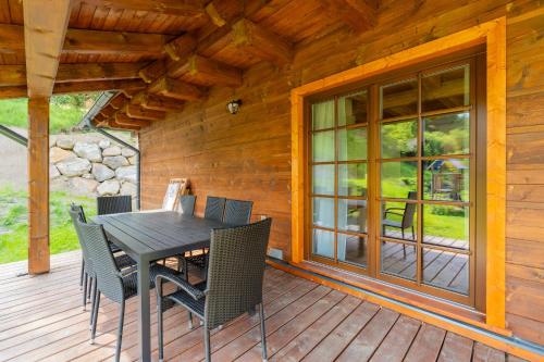 a wooden porch with a table and chairs on a deck at Dvě chalupy - Velké Karlovice in Velké Karlovice