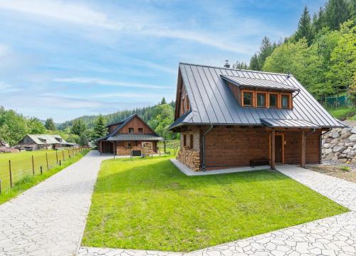 a house with a metal roof and a grass yard at Dvě chalupy - Velké Karlovice in Velké Karlovice