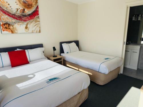 two beds in a small room with white walls at Beachcomber Motel & Apartments in Apollo Bay