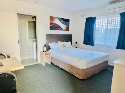 a bedroom with a large bed and blue curtains at Beachcomber Motel & Apartments in Apollo Bay