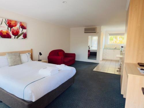 a bedroom with a large bed and a red chair at Beachcomber Motel & Apartments in Apollo Bay