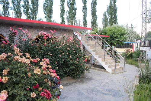 a brick building with a staircase next to flowers at Grandview Hotel skardu in Skardu