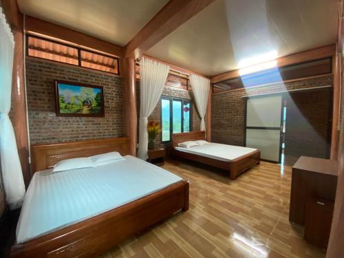a bedroom with two beds and a brick wall at Thung Din Homestay in Phủ Nho Quan