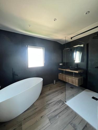 La salle de bains est pourvue d'une grande baignoire blanche et d'une fenêtre. dans l'établissement Villa avec piscine et SPA, à Saint-Gilles-Croix-de-Vie