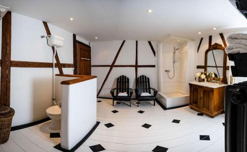 a bathroom with a toilet and a tub and two chairs at Strömbergs Gunnar in Oberstaufen