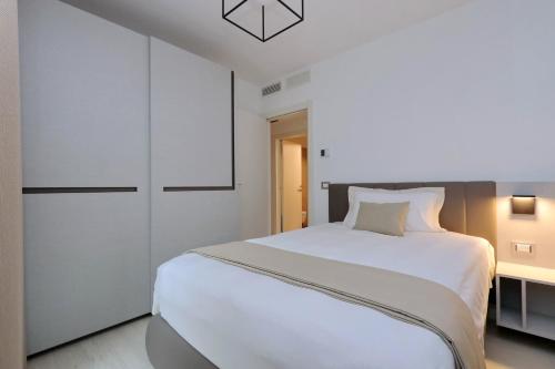 a bedroom with a white bed and a white cabinet at Portopiccolo Apartments in Sistiana