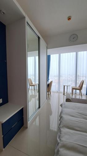 a bedroom with a bed and a balcony with chairs at Blue Belle Staycation Pollux Habibie in Batam Center