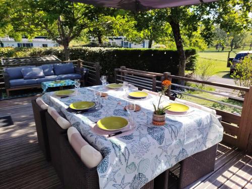 une table avec une nappe verte et blanche sur une terrasse dans l'établissement Le coin des amis, à Biscarrosse