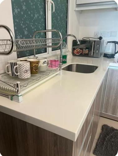 a kitchen counter with a sink and a shelf with cups at GA Homes Homestay - Majestic Ipoh Condo in Ipoh
