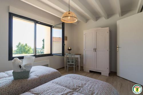 two beds in a bedroom with windows and a table at Gîte la selve d'autan in Caraman
