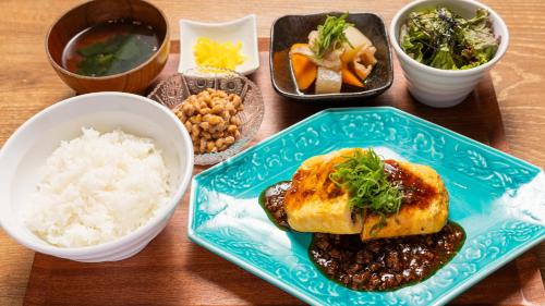 a table with a plate of food and bowls of rice at APA Hotel Nambaminami Daikokucho Ekimae in Osaka
