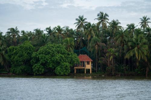 a small house on the shore of a body of water at SaffronStays Suvarna Sangam, Udupi in Udupi