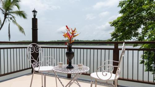 two chairs and a table with a vase on a balcony at SaffronStays Suvarna Sangam, Udupi in Udupi