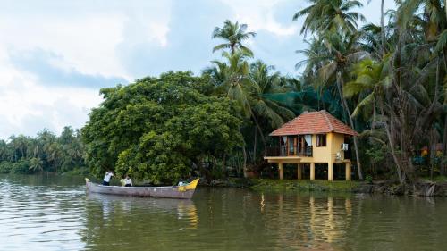 two people in a boat on a river with a house at SaffronStays Suvarna Sangam, Udupi in Udupi