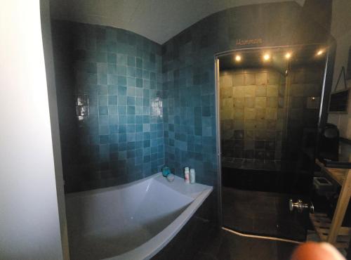 a bathroom with a tub and a shower with blue tiles at Villa Namasté SPA Hammam port & Mer in La Trinité-sur-Mer