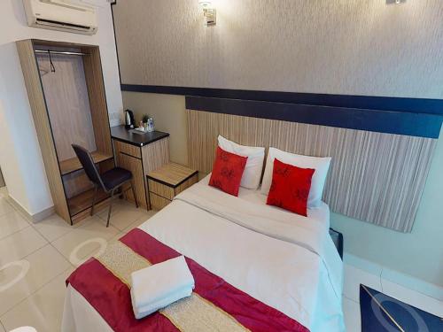 a bedroom with a bed with red pillows and a desk at Aster+ Hotel Bukit Jalil in Kuala Lumpur