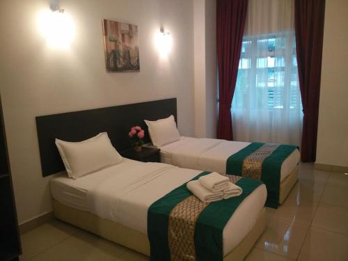 a hotel room with two beds and a window at Aster+ Hotel Bukit Jalil in Kuala Lumpur
