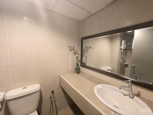 a bathroom with a toilet and a sink and a mirror at Aster+ Hotel Bukit Jalil in Kuala Lumpur