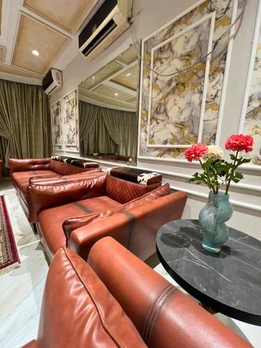 a waiting room with leather couches and a table and flowers at LUXURY family cottage in Islamabad