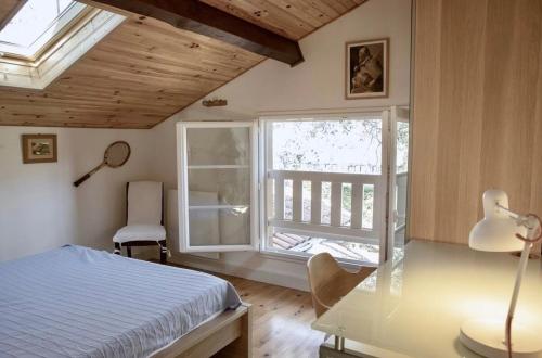 une chambre avec un lit, un bureau et une fenêtre dans l'établissement Maison 11p au calme avec clim et piscine, à Lacanau