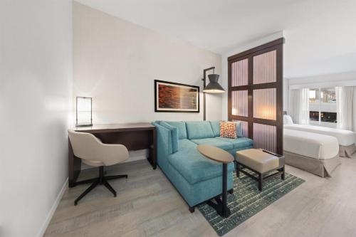 a living room with a blue couch and a desk at Hyatt Place West Palm Beach in West Palm Beach