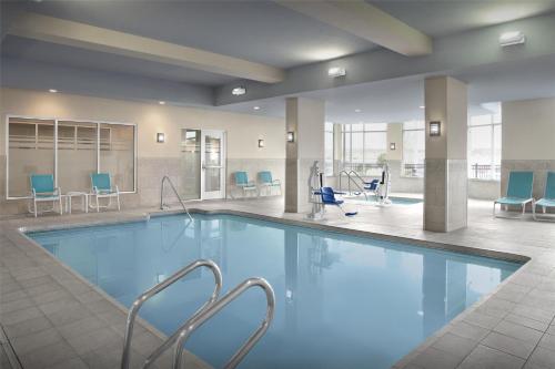 a swimming pool in a hotel lobby with chairs and tables at Hilton Garden Inn Gallup in Gallup