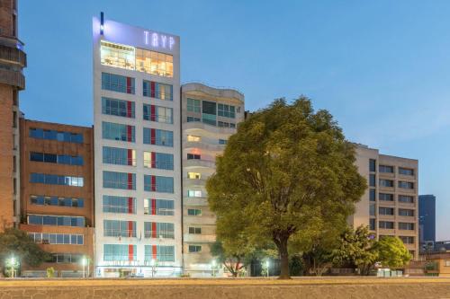 a tall building with a tree in front of it at TRYP by Wyndham Mexico City World Trade Center Area in Mexico City