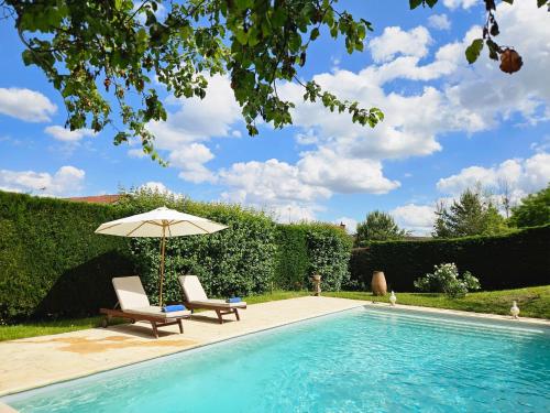 une piscine avec deux chaises et un parasol dans l'établissement Maisons du Cerf et du Tilleul, à Châtillon-sur-Cher