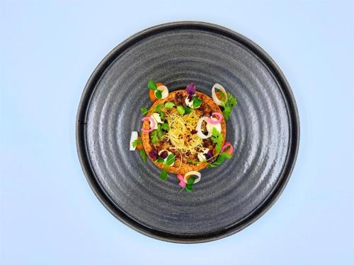 a black plate with a dish of food on it at Grand Hotel des Bains Kempinski in St. Moritz