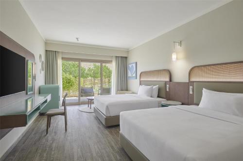 a hotel room with two beds and a flat screen tv at Doubletree By Hilton Mangroovy El Gouna Resort in Hurghada