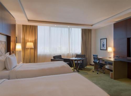 a hotel room with two beds and a desk at Grand Mogador City Center in Casablanca