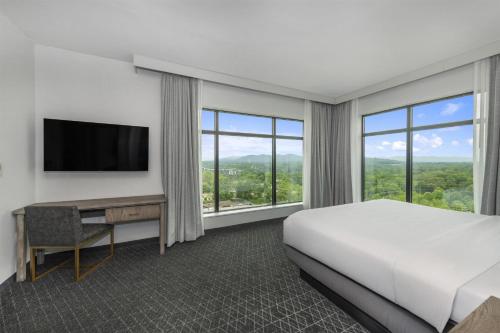 a hotel room with a bed and a desk with a television at Embassy Suites By Hilton Asheville Downtown in Asheville