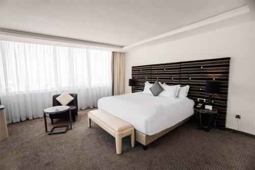 a hotel room with a large bed and a chair at Grand Mogador City Center in Casablanca