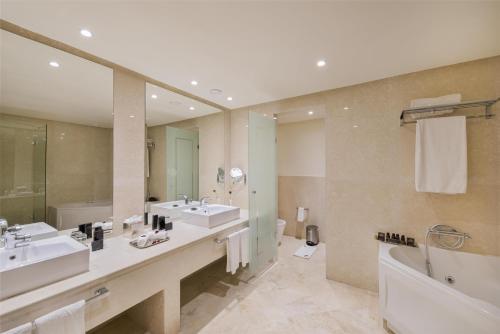 a bathroom with two sinks and a tub and a large mirror at Grand Mogador City Center in Casablanca