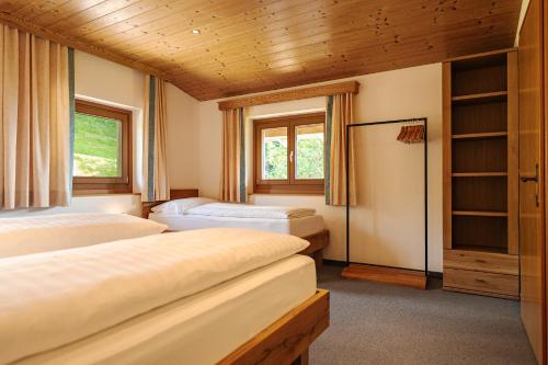 two beds in a room with wooden ceilings and windows at Pension Schlossberg in Mittersill