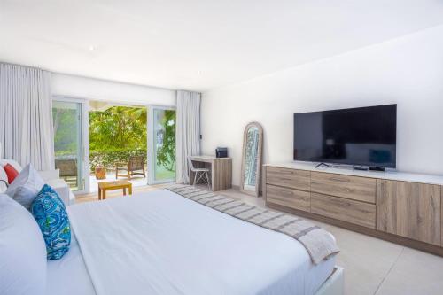 a bedroom with a large bed and a television at Hodges Bay Resort & Spa, an HQ Luxury Resort & Residences in Saint Johnʼs